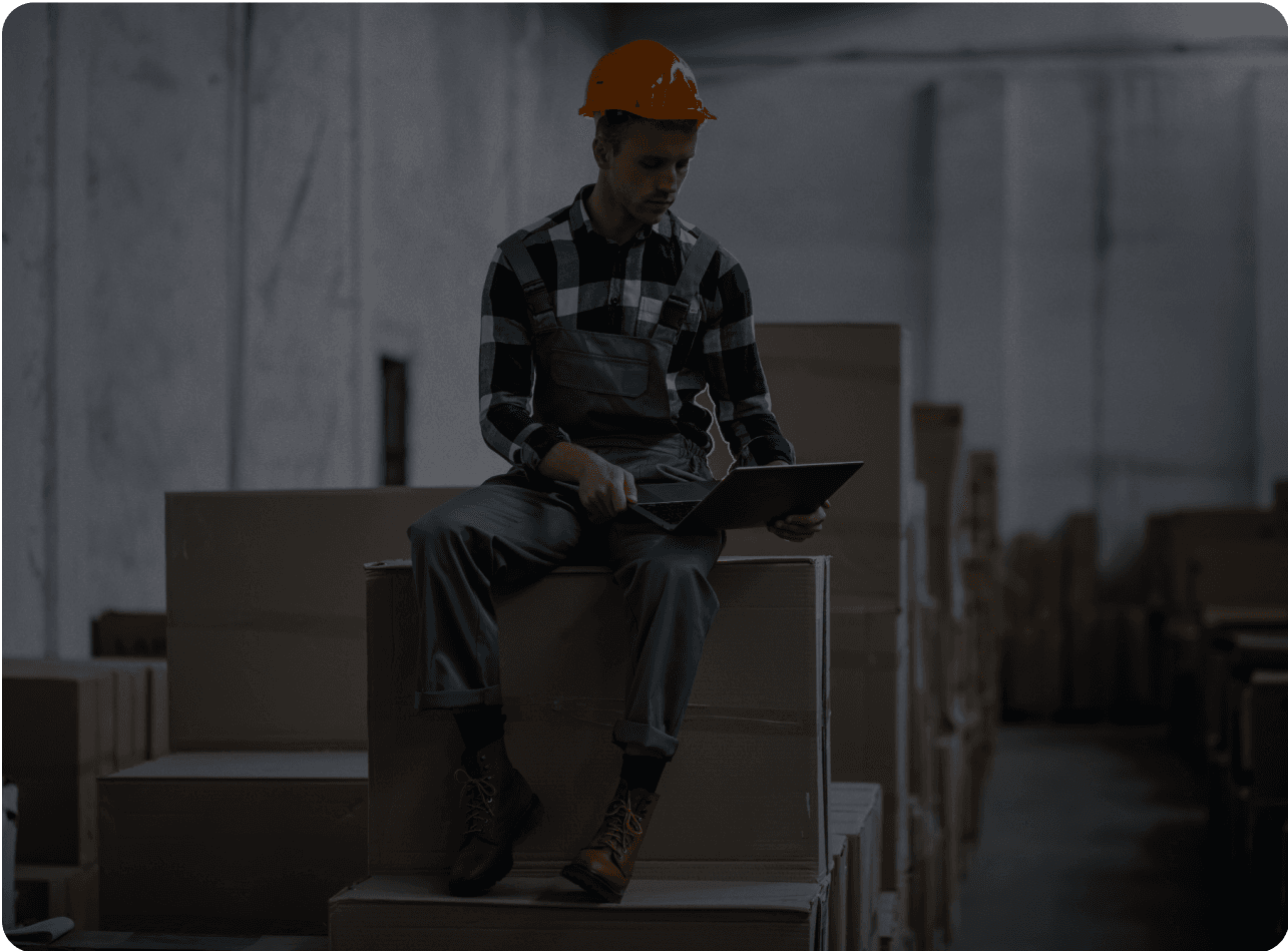 Worker using a laptop in a warehouse, symbolizing outsourcing accounting efficiency.