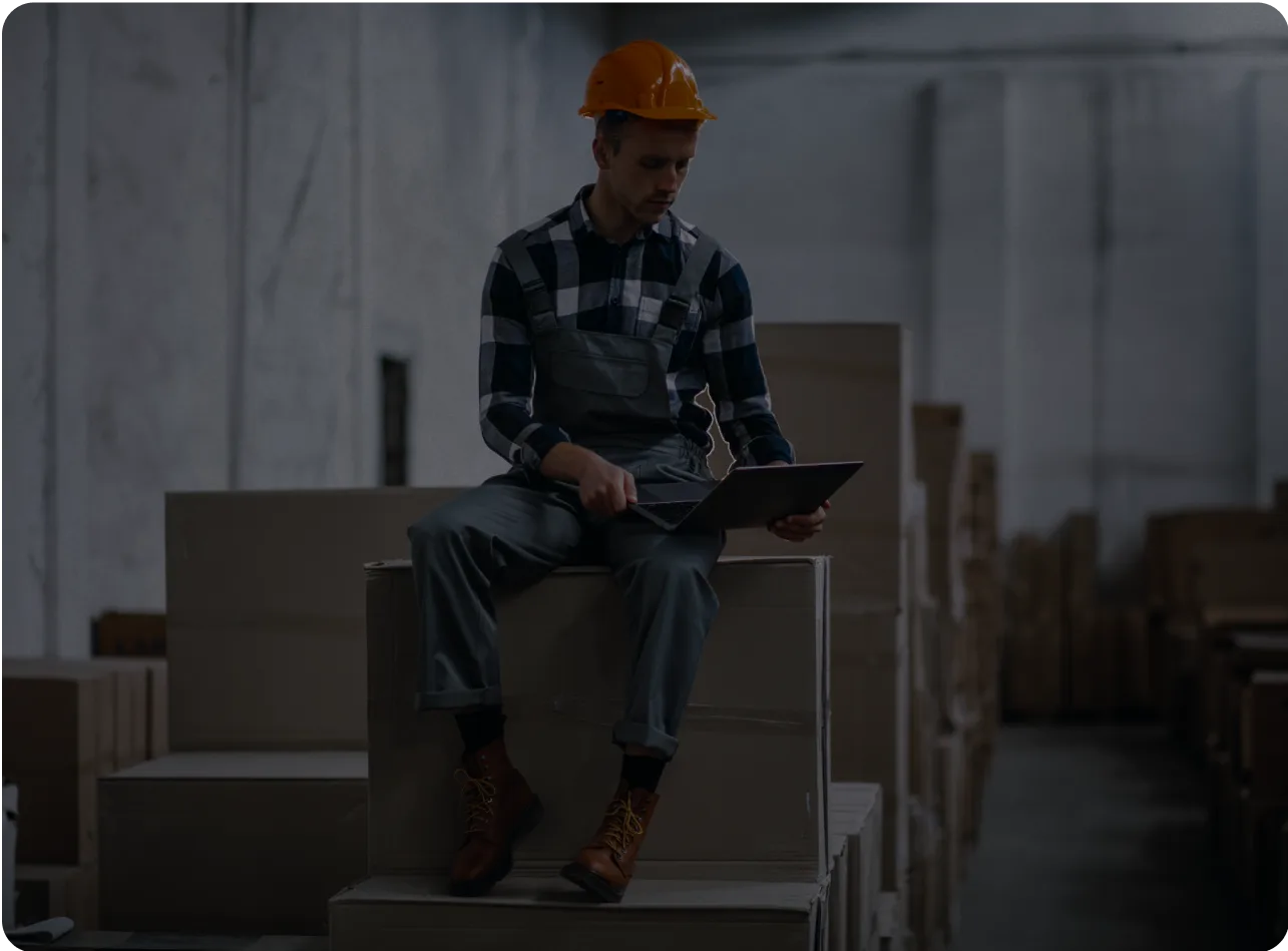Worker using a laptop in a warehouse, symbolizing outsourcing accounting efficiency.