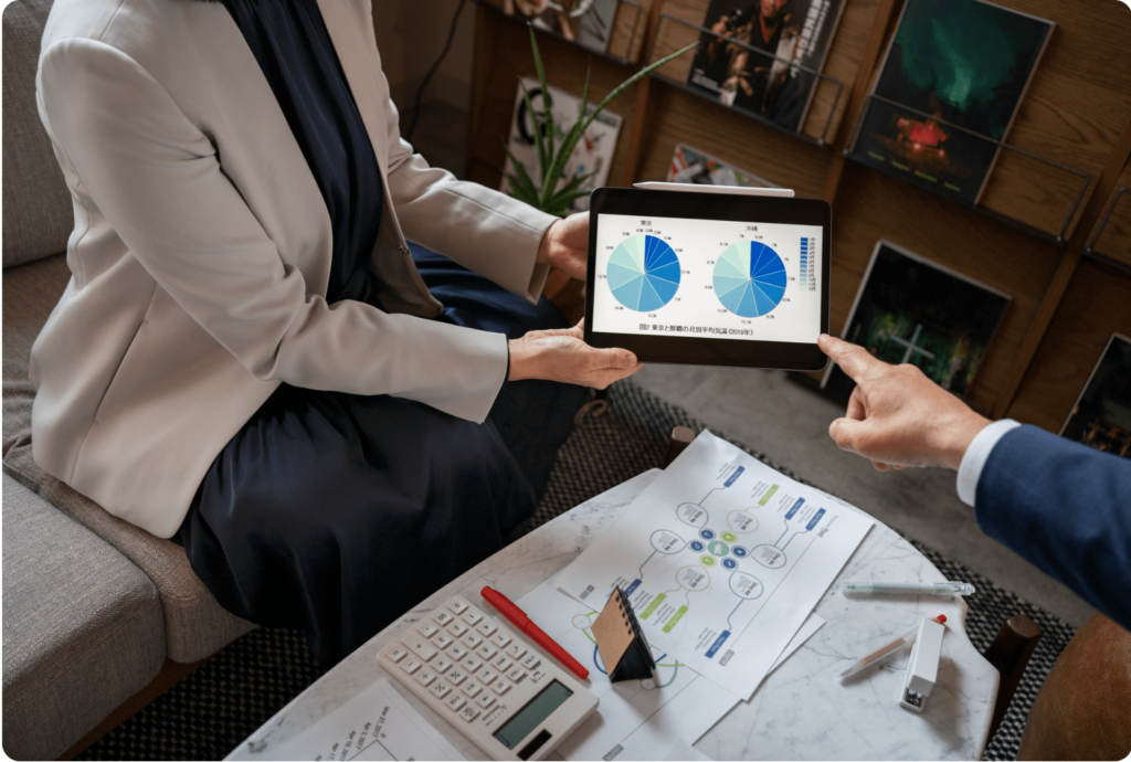 Professionals reviewing pie charts on a tablet with documents and a calculator on the table – expertise accelerated in financial analysis.