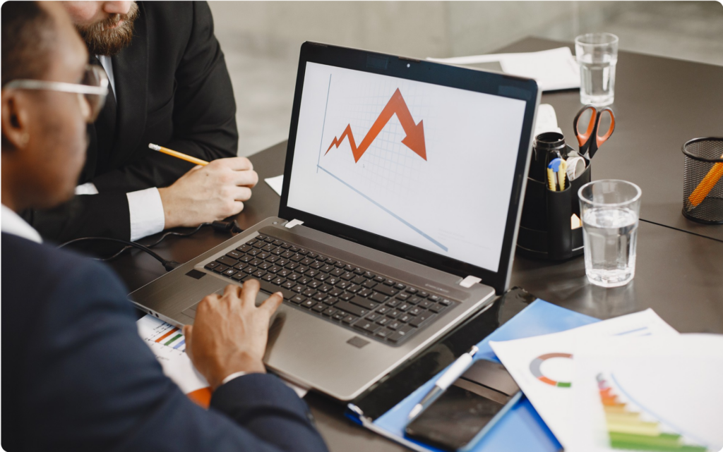 Team analyzing a downward graph on a laptop screen with charts and documents – general accounting discussion.