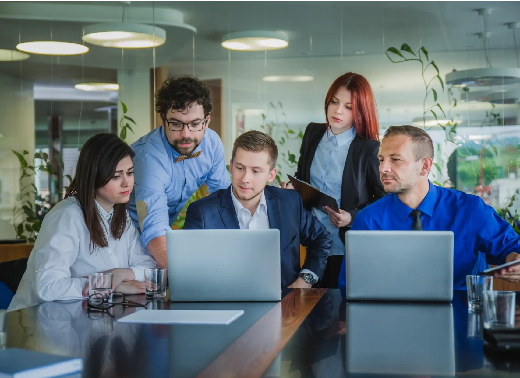 Team of professionals collaborating on laptops, showcasing expertise in accelerated and outsourced accounting services within a modern office environment